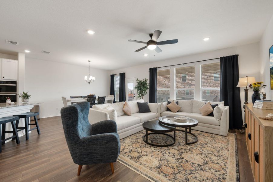 Living area featuring dark wood finished floors, a ceiling fan, and hanging lights