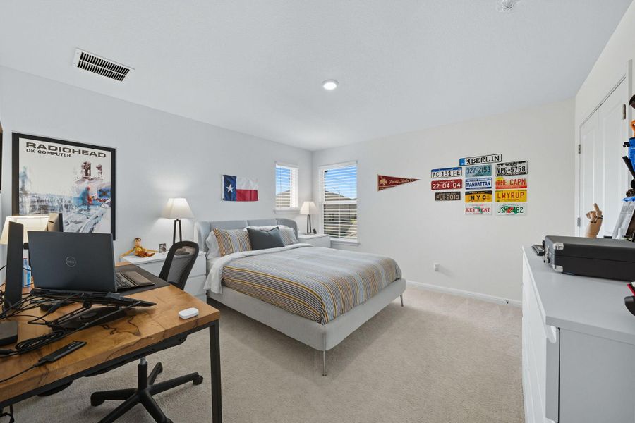 Bedroom with an office area and light carpet Bedroom with an office area and light carpet