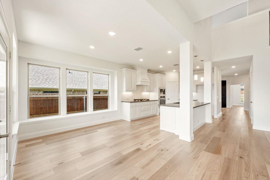 Open-concept living area and kitchen with white cabinets, dark countertops, and light hardwood floors Open-concept living area and kitchen with white cabinets, dark countertops, and light hardwood floors