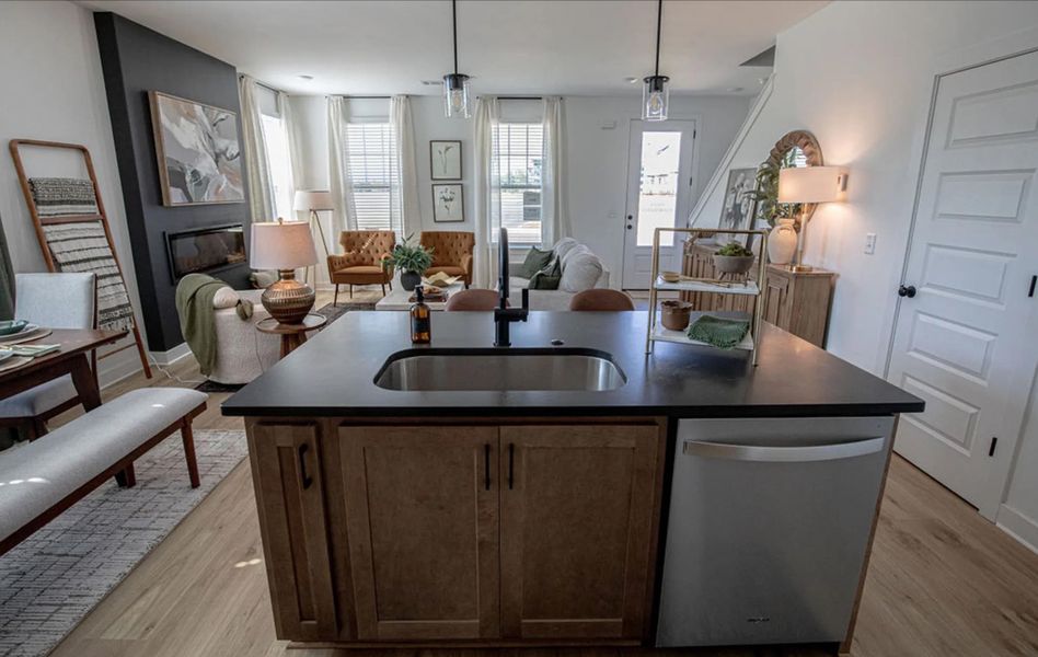 Kitchen featuring an island with sink, dishwasher, open floor plan, and light wood-style flooring