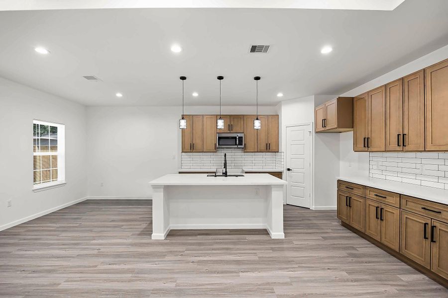 Modern kitchen with sleek cabinetry, a spacious island with pendant lighting, and stylish white subway tile backsplash.