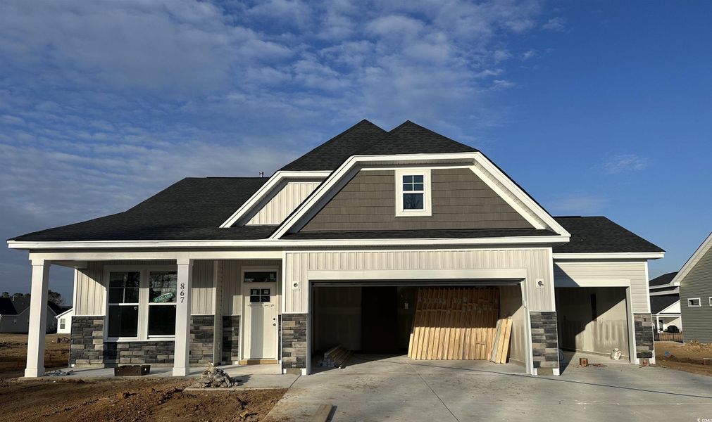 Unfinished property with roof with shingles, covered porch, concrete driveway, and board and batten siding