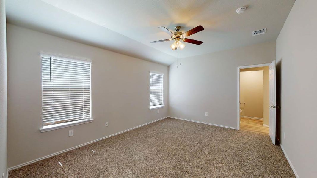 A well-lit bedroom with soft carpet flooring and a ceiling fan for comfort. A well-lit bedroom with soft carpet flooring and a ceiling fan for comfort.