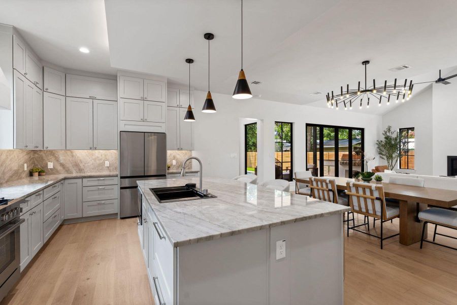 An open-concept living space with a pristine kitchen island and elegant pendant lighting. An open-concept living space with a pristine kitchen island and elegant pendant lighting.