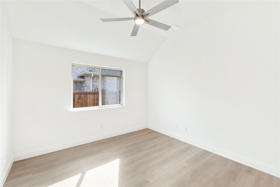 Empty bedroom with vaulted ceiling, ceiling fan, hardwood floors, and single window Empty bedroom with vaulted ceiling, ceiling fan, hardwood floors, and single window