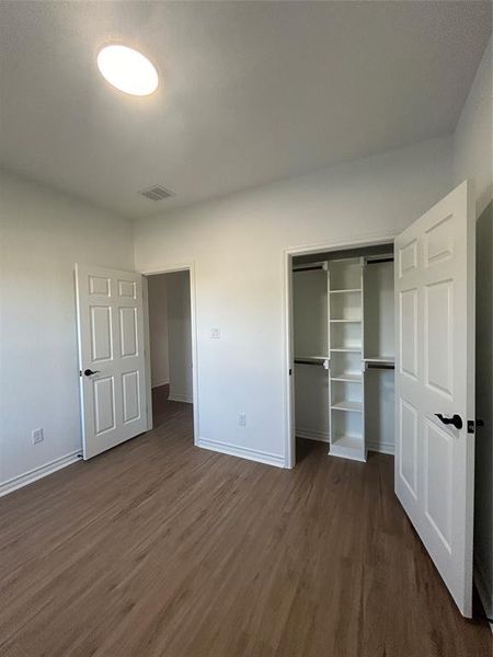 Unfurnished bedroom featuring a closet and dark hardwood / wood-style floors