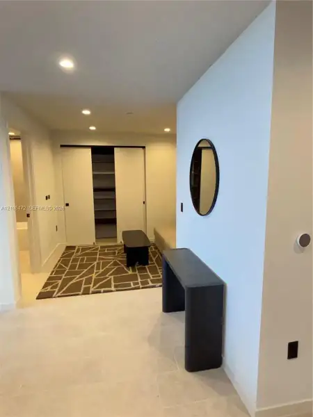 Built-in closet with sliding doors and integrated shelving, recessed lighting, and neutral stone-finish flooring Built-in closet with sliding doors and integrated shelving, recessed lighting, and neutral stone-finish flooring
