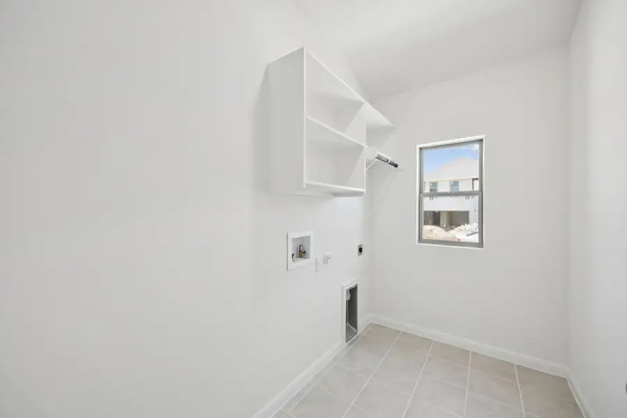 Washroom featuring gas dryer hookup, hookup for an electric dryer, hookup for a washing machine, and light tile patterned floors
