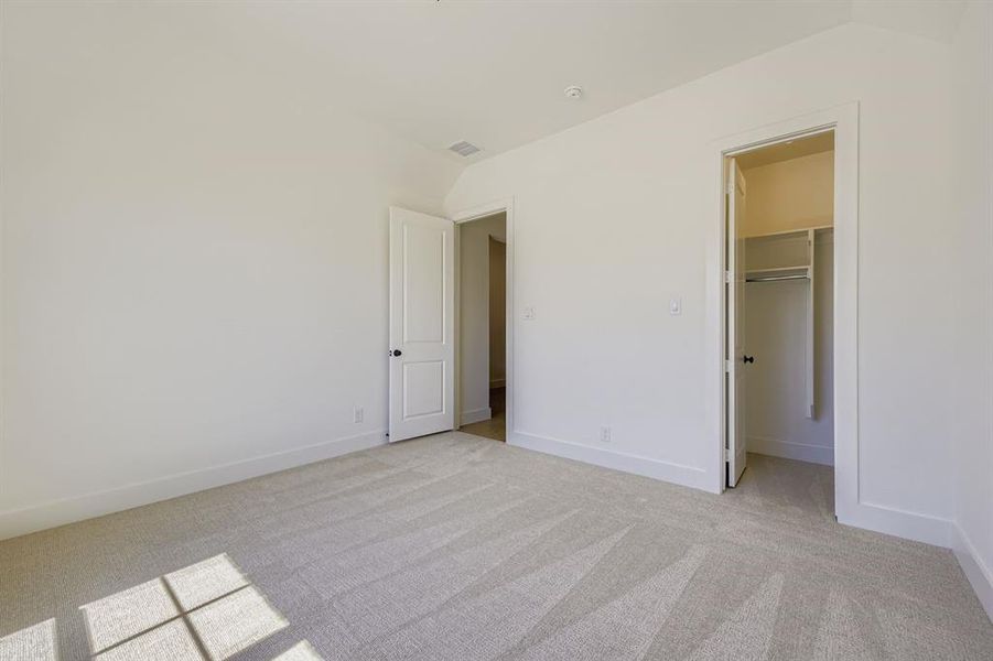 Unfurnished bedroom featuring a walk in closet and light colored carpet Unfurnished bedroom featuring a walk in closet and light colored carpet