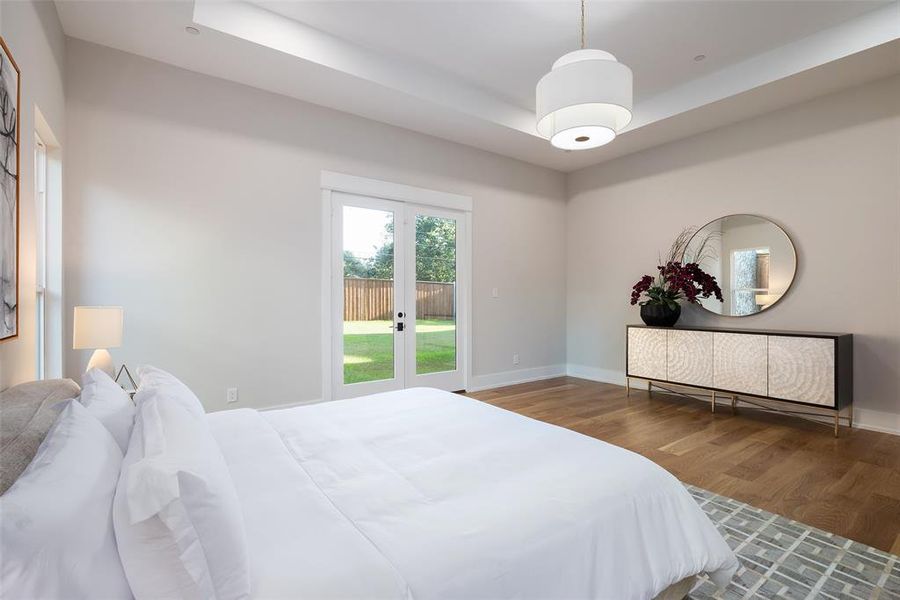 Bedroom with hardwood / wood-style flooring, french doors, and a tray ceiling