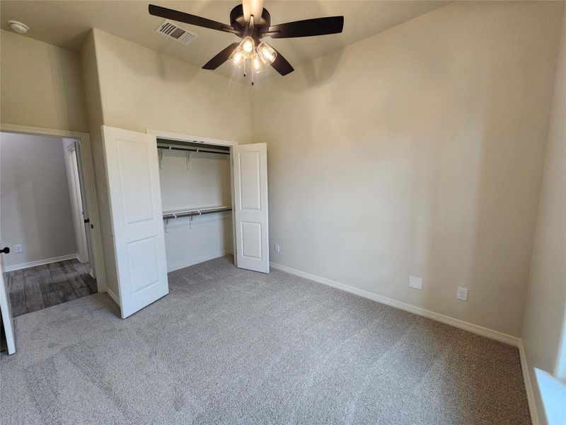 Bedroom featuring neutral-toned walls, gray carpet flooring, and a ceiling fan with integrated lighting