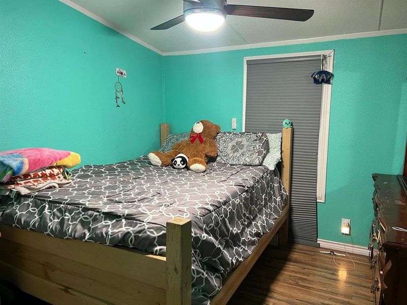 Bedroom featuring ceiling fan, dark hardwood / wood-style floors, and ornamental molding