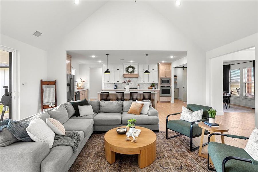 Living room featuring high vaulted ceiling and light hardwood / wood-style flooring