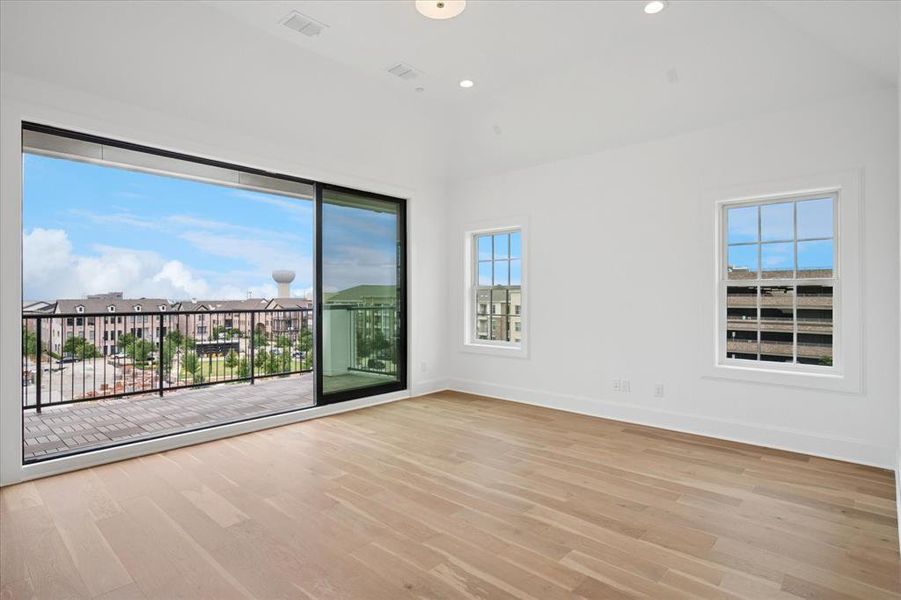 Spacious room featuring light wood-finish flooring, white walls, and a recessed lighting fixture