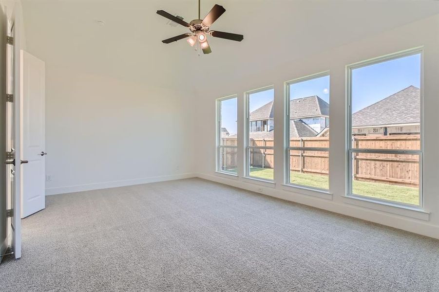 Carpeted empty room with plenty of natural light and ceiling fan