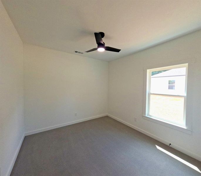 Unfurnished room with dark carpet and a ceiling fan Unfurnished room with dark carpet and a ceiling fan