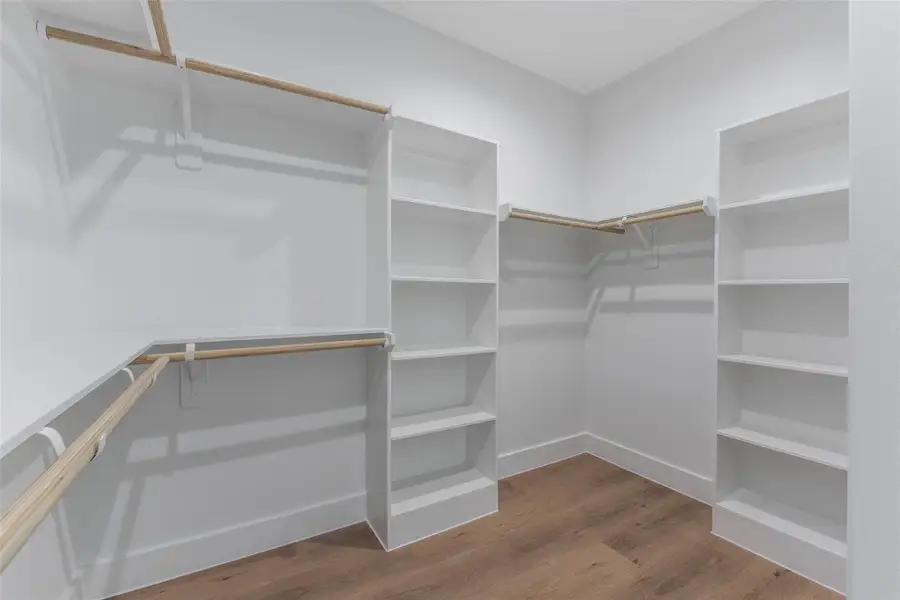 An ample walk-in closet featuring built-in shelving and generous hanging space, thoughtfully designed for organized, effortless storage. An ample walk-in closet featuring built-in shelving and generous hanging space, thoughtfully designed for organized, effortless storage.