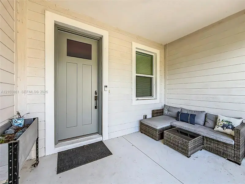 Covered porch featuring horizontal lap siding, a solid entry door with an upper glass pane, and a single-hung window with wide white trim