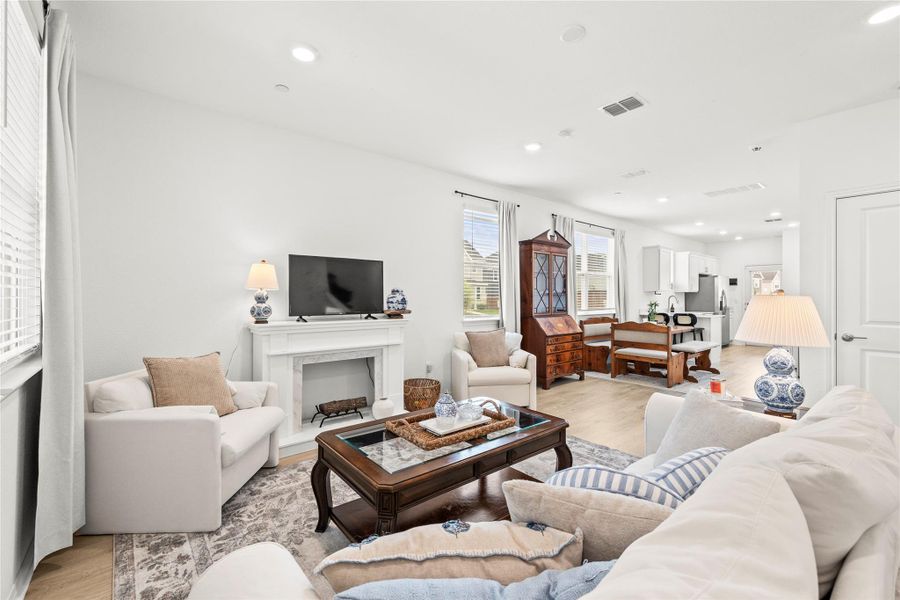 A well-lit great room features an elegant fireplace and offers a seamless transition to the kitchen and dining area.