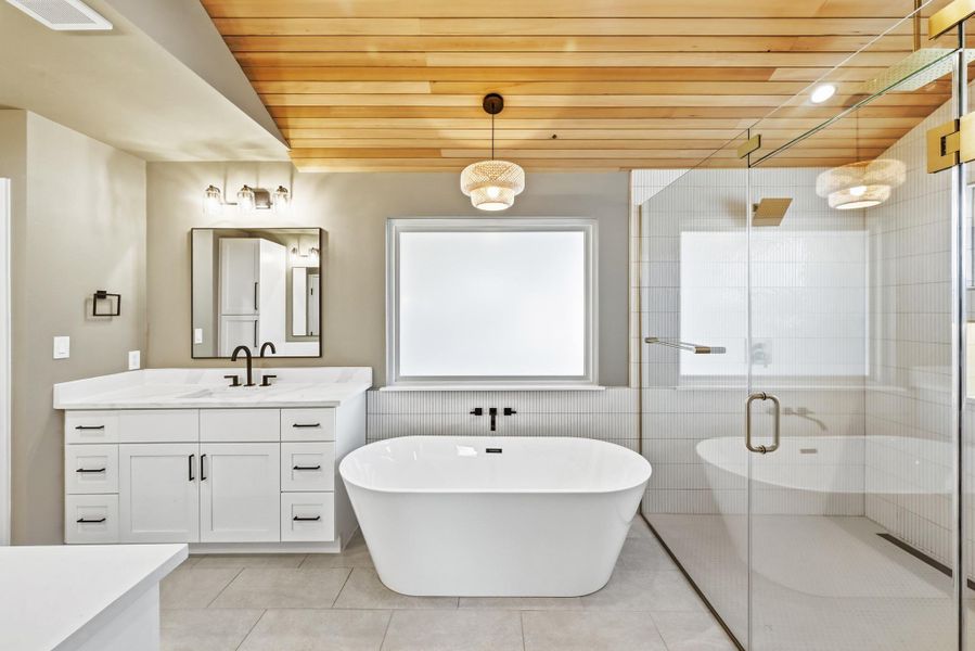 Bathroom featuring vanity, a freestanding bath, wood ceiling, a stall shower, and tile walls