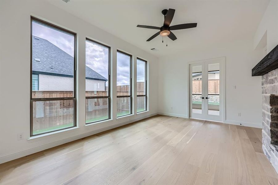 Unfurnished living room with light hardwood / wood-style flooring, a stone fireplace, and plenty of natural light