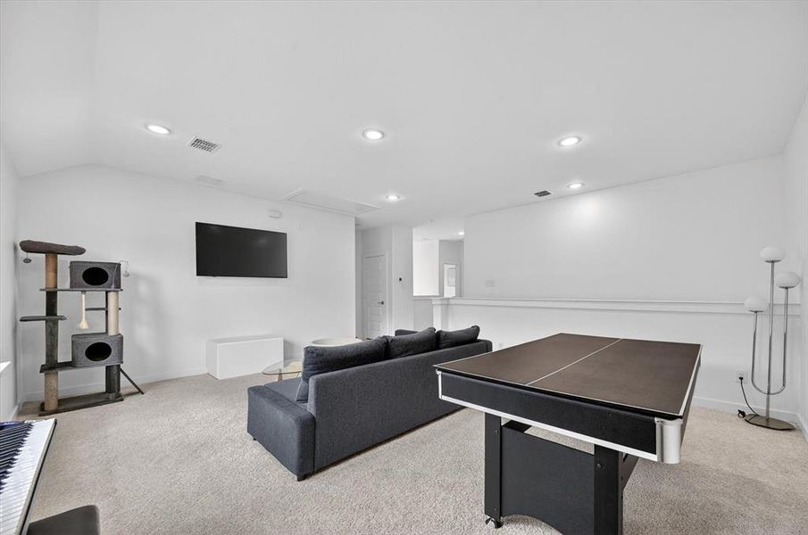 Spacious room featuring neutral carpet flooring, recessed lighting, and a sloped ceiling