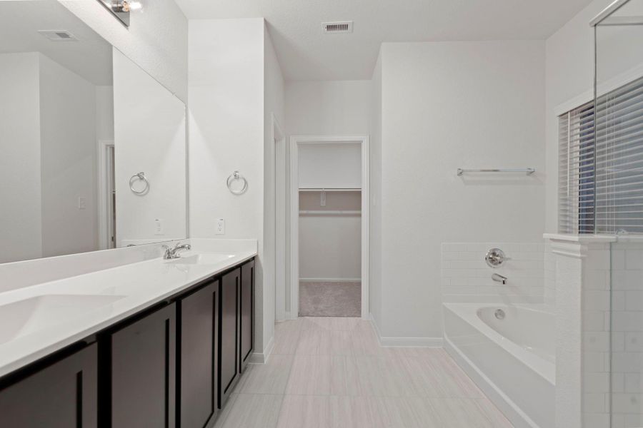 The luxurious primary bath features a long dual-sink vanity, sleek cabinetry, and modern fixtures. This spacious layout offers both functionality and style, ideal for busy mornings or relaxing evening routines.  Wait till you see the massive walk in closet!