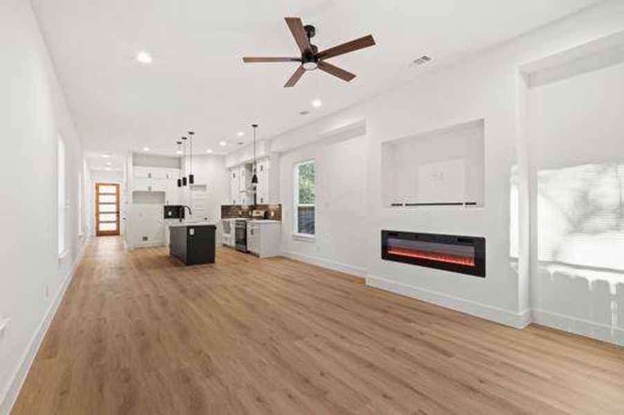 Unfurnished living room with ceiling fan and light wood-type flooring