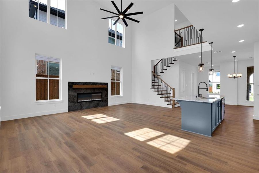 Unfurnished living room featuring stairs, a fireplace, ceiling fan, dark wood-style flooring, and a high ceiling Unfurnished living room featuring stairs, a fireplace, ceiling fan, dark wood-style flooring, and a high ceiling