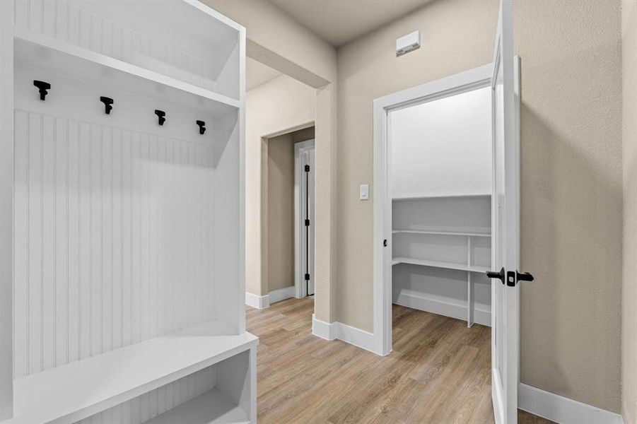 Built-in storage features a white beadboard mudroom bench with upper shelving and coat hooks, complemented by wood-finish flooring