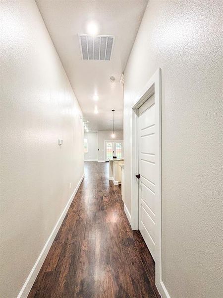Corridor featuring dark wood finished floors and a textured wall Corridor featuring dark wood finished floors and a textured wall
