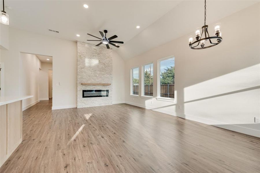 Unfurnished living room with a fireplace, light wood finished floors, a chandelier, recessed lighting, and a ceiling fan