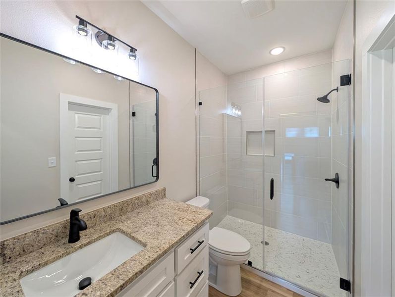 Full bath with vanity, a stall shower, wood finished floors, and recessed lighting Full bath with vanity, a stall shower, wood finished floors, and recessed lighting