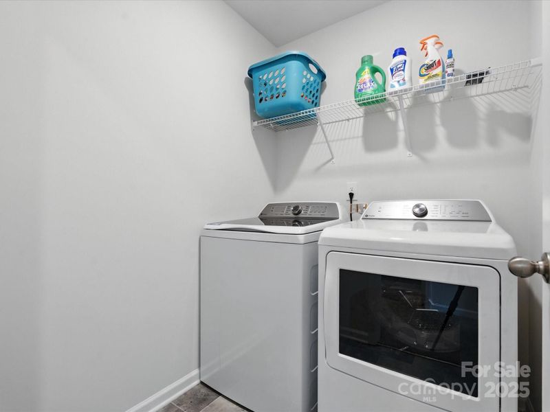 Dedicated laundry room with side-by-side washer and dryer, wire shelving for storage, and convenient supplies organization. Separate laundry space adds functionality and keeps utility areas organized.