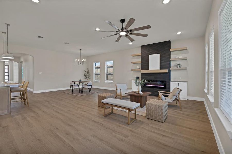 Living room featuring a large fireplace, arched walkways, recessed lighting, ceiling fan, and baseboards Living room featuring a large fireplace, arched walkways, recessed lighting, ceiling fan, and baseboards