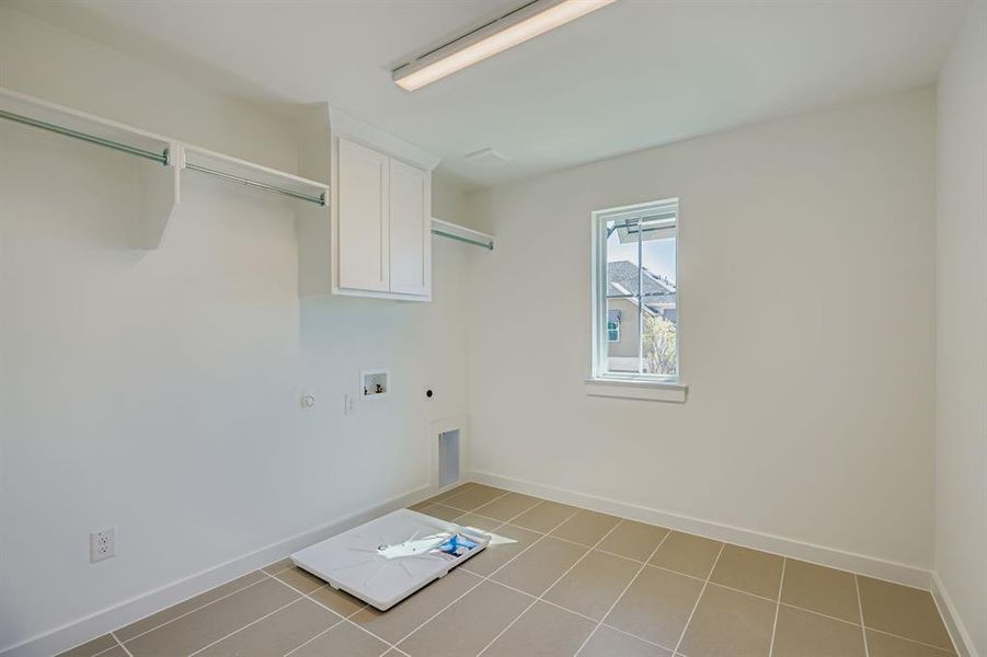 Washroom with gas dryer hookup, hookup for an electric dryer, light tile patterned floors, hookup for a washing machine, and cabinet space Washroom with gas dryer hookup, hookup for an electric dryer, light tile patterned floors, hookup for a washing machine, and cabinet space