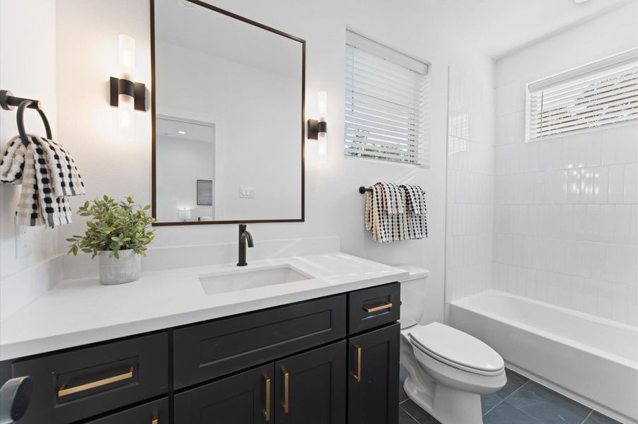 Modern townhomes with sleek lines and contrasting materials, featuring expansive windows and spacious two-car garages, set in a contemporary neighborhood.
