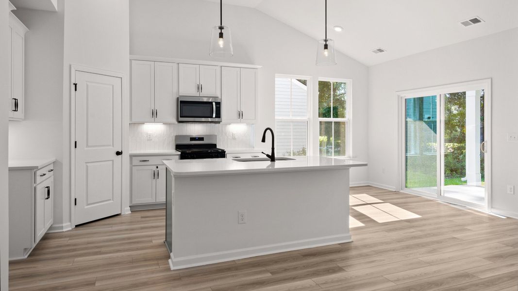 A chef’s kitchen with quartz countertops, a large island, and walk-in pantry