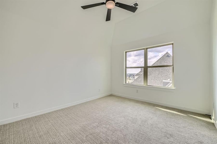 Carpeted empty room featuring a towering ceiling and ceiling fan