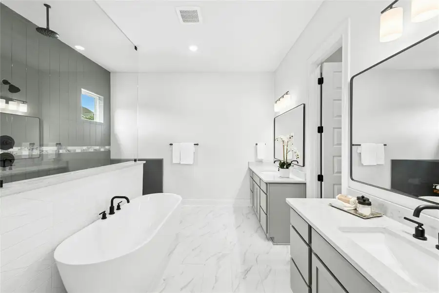 Full bathroom with a freestanding bath, two vanities, walk in shower, light marble finish floors, and recessed lighting Full bathroom with a freestanding bath, two vanities, walk in shower, light marble finish floors, and recessed lighting
