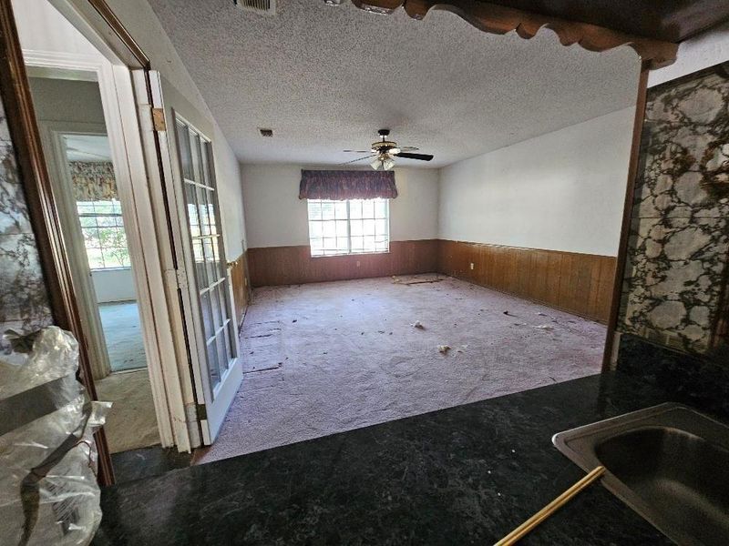 Unfurnished room with wainscoting, carpet, a textured ceiling, and wood walls Unfurnished room with wainscoting, carpet, a textured ceiling, and wood walls