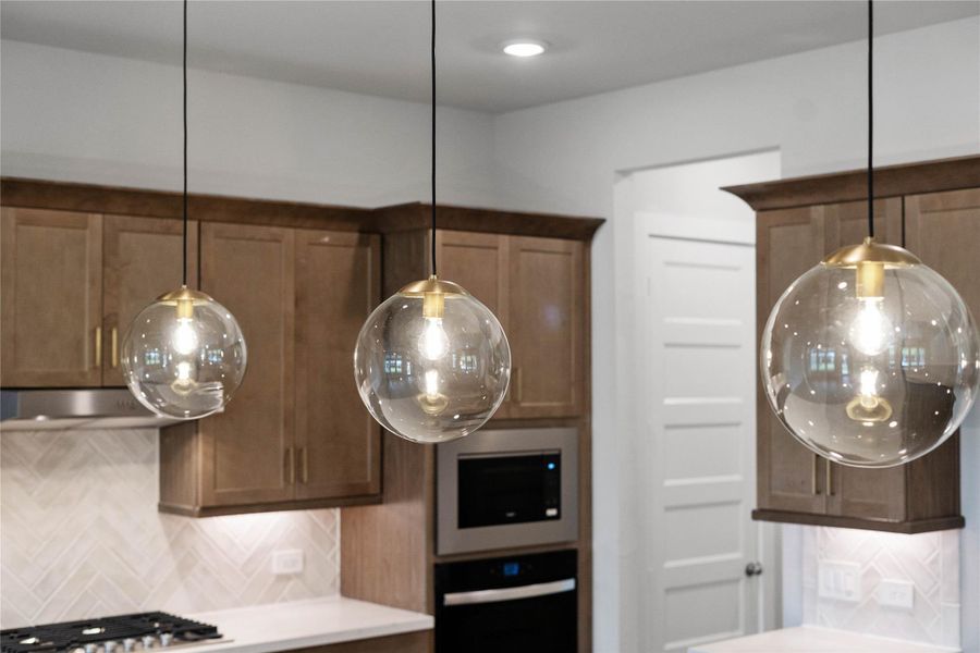 The Atwell brushed bronze pendant light fixtures located over the kitchen countertop gives added light into the kitchen - adding a sleek, reflective accent.