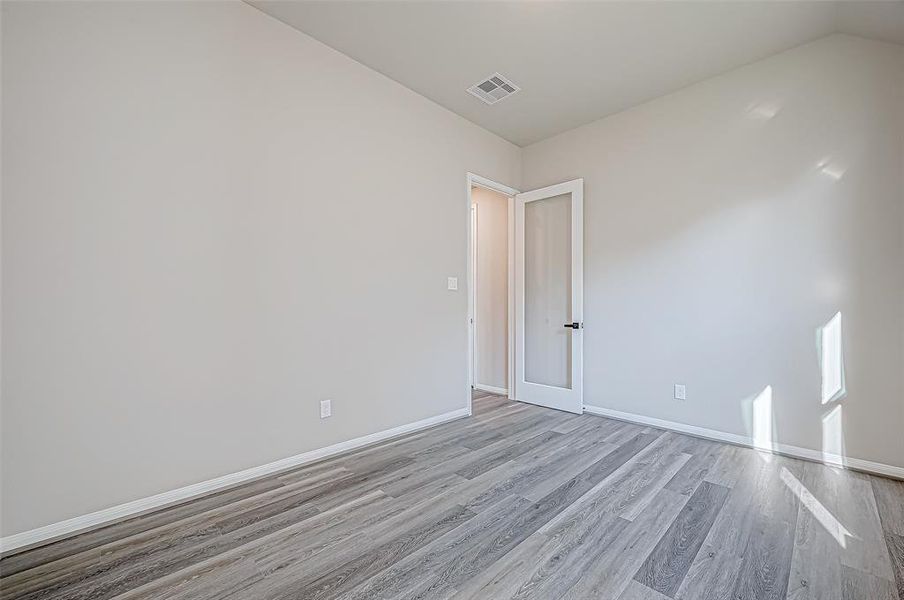 A versatile home office with a glass-framed door provides the perfect work space or workout area.