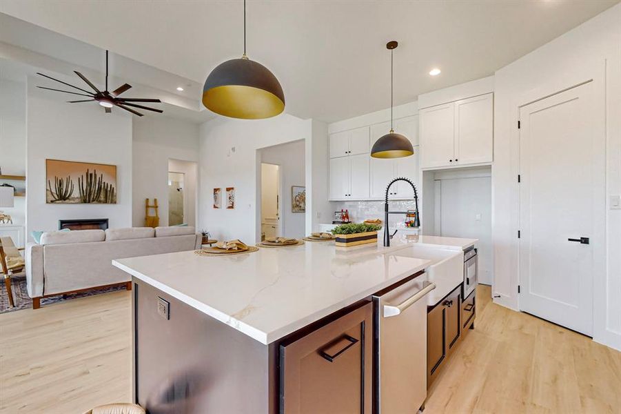 Kitchen with dishwasher, a center island with sink, white cabinetry, and light hardwood / wood-style flooring