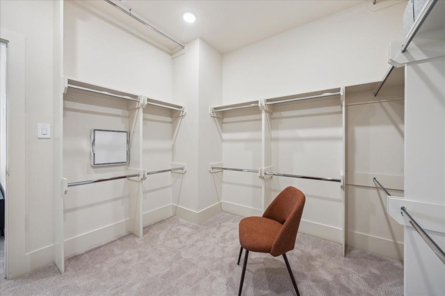 This walk-in closet offers generous storage space with multiple hanging areas and built-in shelving to keep everything organized.