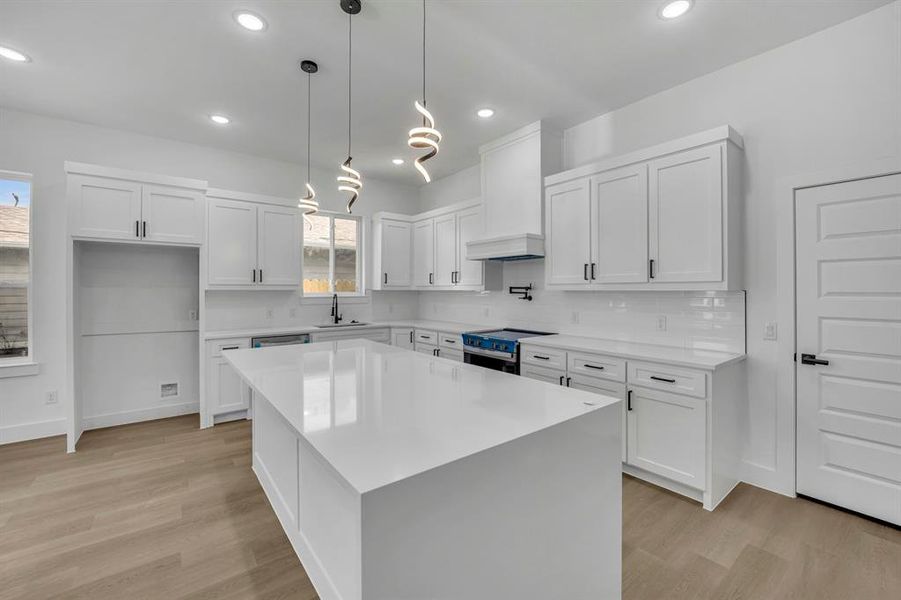 Kitchen featuring stainless steel appliances, white cabinetry, a center island, and sink