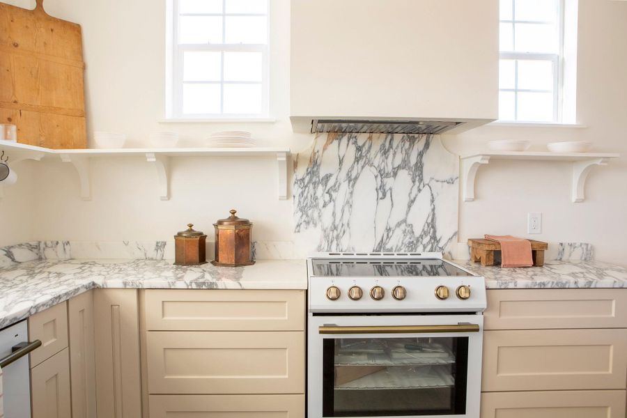 Kitchen with high end stove, custom range hood, light stone counters, and cream cabinets Kitchen with high end stove, custom range hood, light stone counters, and cream cabinets