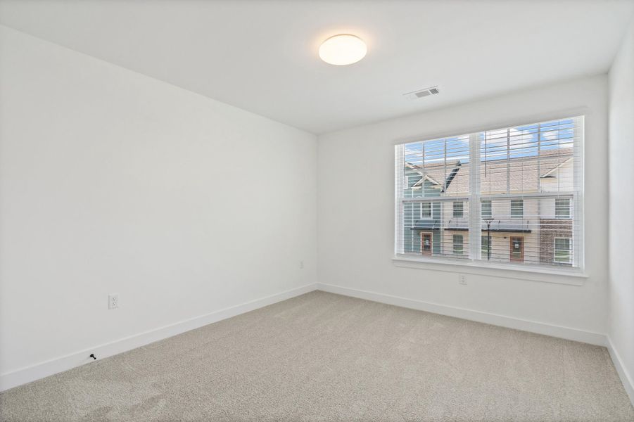 Neutral tone carpeting with white baseboards and walls