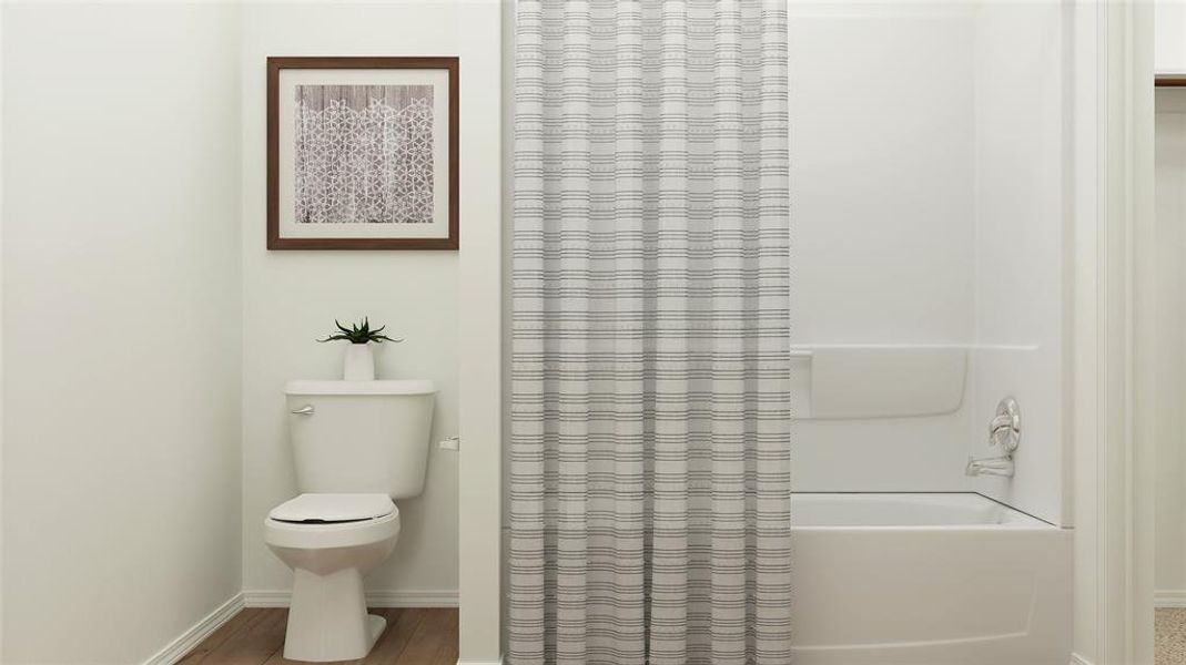 Bathroom with hardwood / wood-style floors, shower / tub combo, and toilet