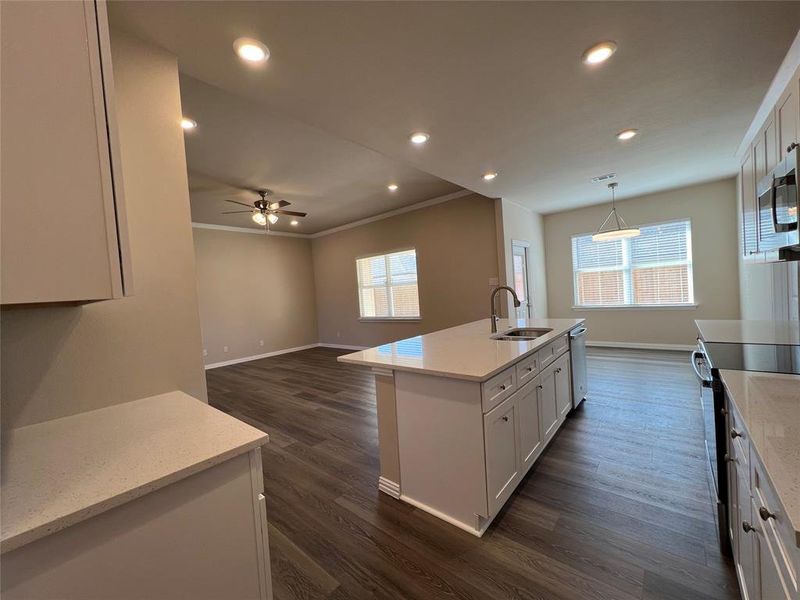 Kitchen with a wealth of natural light, a center island with sink, and dark hardwood / wood-style floors